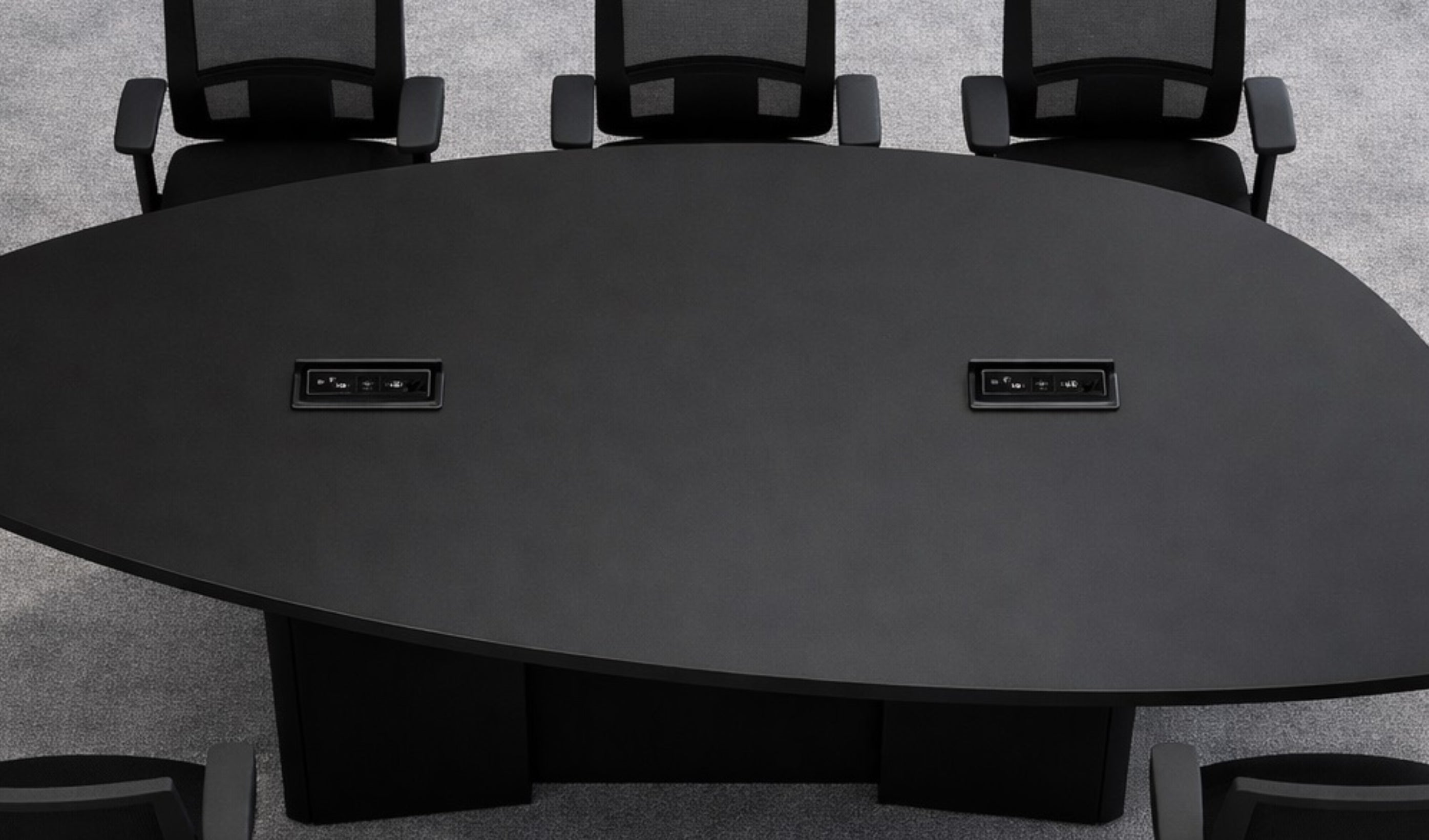 Black conference table with power outlets and six chairs arranged around it.