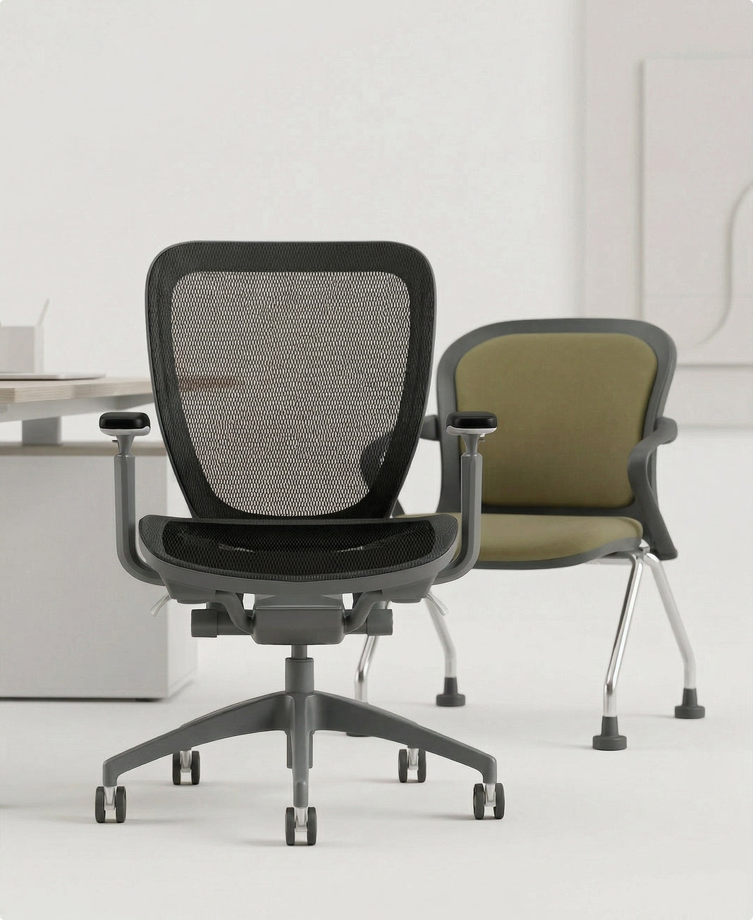 Two office chairs, one black mesh and one green cushioned, in a minimalistic office setting.