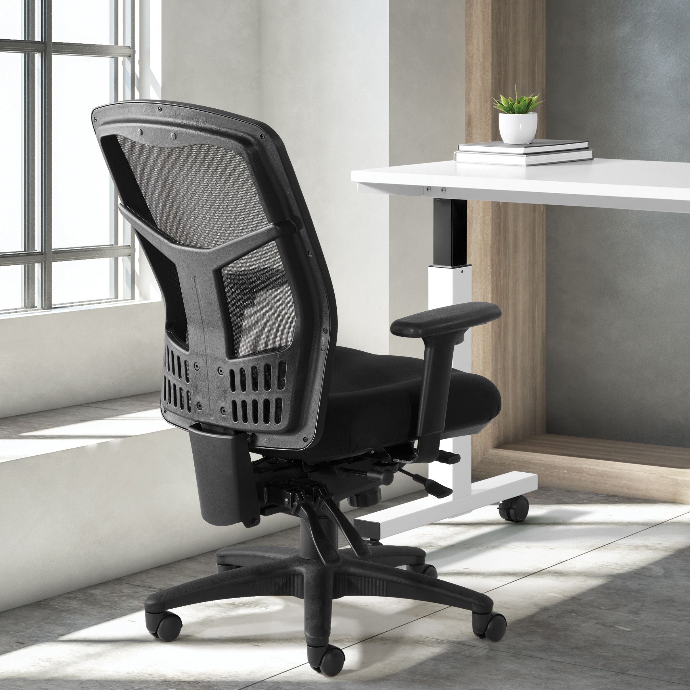 Black office chair in a modern office setting with a desk and window.